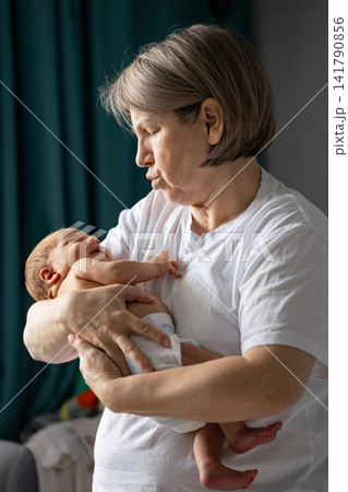 Grandmother holding newborn baby symbolizing love and family bond Grandmother holding newborn baby symbolizing love and family bond 141790856
