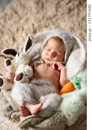 Newborn baby sleeping in bunny outfit holding plush toy Newborn baby sleeping in bunny outfit holding plush toy 141791086