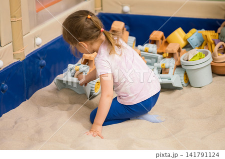 Child playing with toy truck in indoor sandbox 141791124