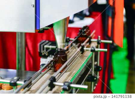 Automatic pill bottle filling machine on conveyor belt in pharmaceutical factory packaging line 141791138