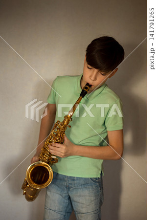 Young boy playing a golden saxophone, learning music instrument Young boy playing a golden saxophone, learning music instrument 141791265