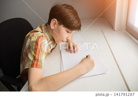 Young boy studying and writing homework on desk Young boy studying and writing homework on desk 141791287