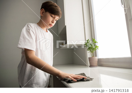 Boy cleaning kitchen surface learning household chores Boy cleaning kitchen surface learning household chores 141791318