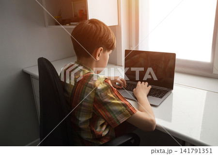 Boy using laptop for remote learning at home desk Boy using laptop for remote learning at home desk 141791351