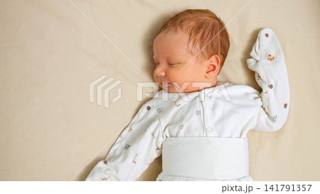 Newborn baby sleeping comfortably during peaceful morning rest Newborn baby sleeping comfortably during peaceful morning rest 141791357