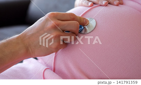Doctor checking pregnant woman's belly with stethoscope during prenatal exam Doctor checking pregnant woman's belly with stethoscope during prenatal exam 141791359