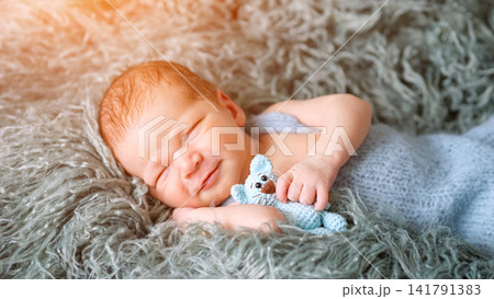 Newborn baby sleeping peacefully holding knitted toy Newborn baby sleeping peacefully holding knitted toy 141791383