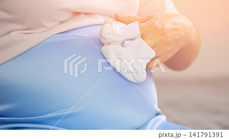Pregnant woman holding baby booties on her baby bump 141791391