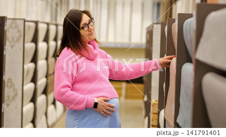 Pregnant woman choosing fabric samples for nursery decor Pregnant woman choosing fabric samples for nursery decor 141791401