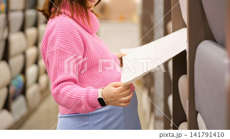 Pregnant woman choosing wallpaper for nursery home renovation Pregnant woman choosing wallpaper for nursery home renovation 141791410