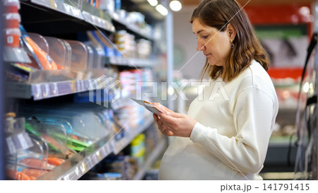 Pregnant woman reading food label for healthy shopping Pregnant woman reading food label for healthy shopping 141791415