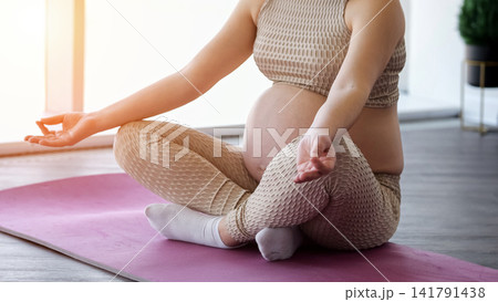 Pregnant woman practicing yoga and meditation for wellness 141791438