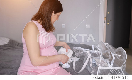 Pregnant woman packing hospital bag, preparing for baby delivery Pregnant woman packing hospital bag, preparing for baby delivery 141791510