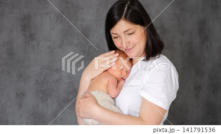 Mother gently holding newborn baby in loving embrace 141791536