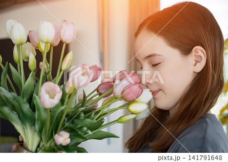 Young girl smelling fresh pink and white tulips bouquet Young girl smelling fresh pink and white tulips bouquet 141791648