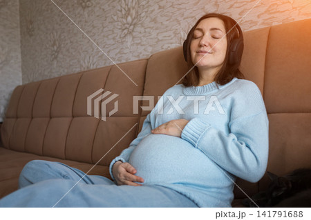 Pregnant woman resting on a sofa at home in warm sunlight Pregnant woman resting on a sofa at home in warm sunlight 141791688