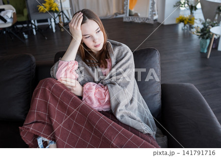 Woman sitting on couch experiencing anxiety and loneliness Woman sitting on couch experiencing anxiety and loneliness 141791716