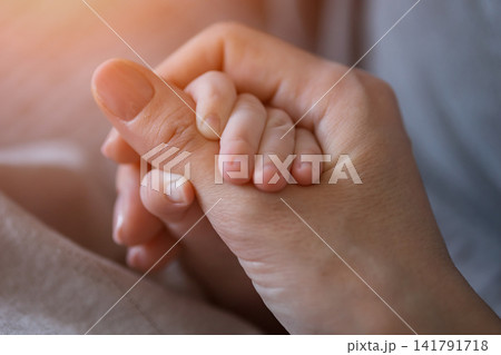 Newborn baby hand holding young mother's finger 141791718