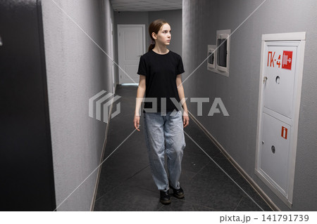 Young girl walking through an empty hallway exploring 141791739