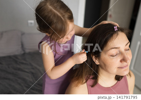 Daughter putting hair clips in mother's hair Daughter putting hair clips in mother's hair 141791795