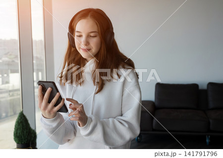 Teen girl listening to music using smartphone and headphones Teen girl listening to music using smartphone and headphones 141791796