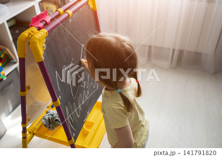 Little girl drawing and learning on a chalkboard easel 141791820