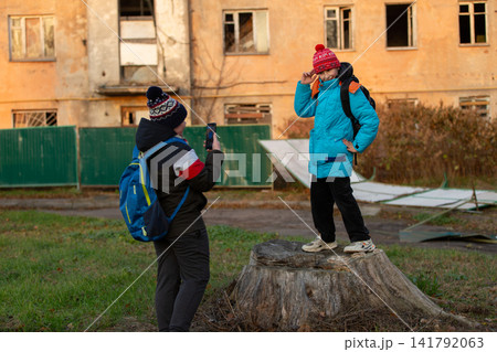 Children wearing winter clothing taking a photo outside an abandoned building Children wearing winter clothing taking a photo outside an abandoned building 141792063