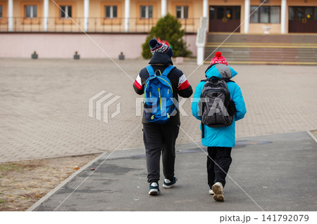 Kids walk together to school on a cold day in a quiet neighborhood after the morning bell rang Kids walk together to school on a cold day in a quiet neighborhood after the morning bell rang 141792079