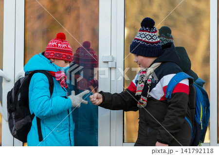 Two children play rock paper scissors outside a school building during a cold winter day Two children play rock paper scissors outside a school building during a cold winter day 141792118