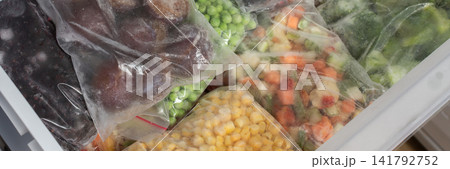 Bags of frozen vegetables fill a refrigerator drawer. Colorful mixes of peas, carrots, and broccoli are ready for cooking. These will be used for meals in winter, banner Bags of frozen vegetables fill a refrigerator drawer. Colorful mixes of peas, carrots, and broccoli are ready for cooking. These will be used for meals in winter, banner 141792752