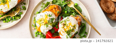This meal features gluten free bread sandwiches topped with zucchini caviar and poached egg. It includes roasted red peppers and green peas, served with baked pears. banner 141792821