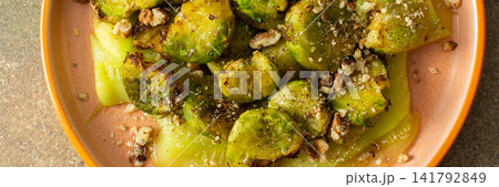 Baked Brussels sprouts are combined with zucchini slices and walnuts. The dish is served on a plate, ready for breakfast or lunch at home, banner Baked Brussels sprouts are combined with zucchini slices and walnuts. The dish is served on a plate, ready for breakfast or lunch at home, banner 141792849