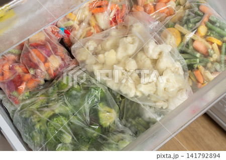 Bags of frozen vegetables fill a refrigerator drawer. Colorful mixes of peas, carrots, and broccoli are ready for cooking. These will be used for meals in winter Bags of frozen vegetables fill a refrigerator drawer. Colorful mixes of peas, carrots, and broccoli are ready for cooking. These will be used for meals in winter 141792894