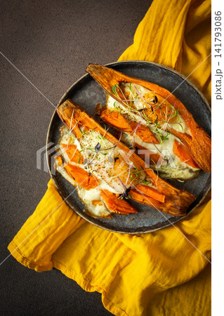 Nutrient-rich eggs baked inside sweet potatoes sit on a rustic plate. Fresh microgreens add a touch of bright color to this healthy meal served in a warm kitchen 141793086