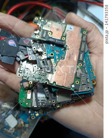Smartphone motherboards that have been disassembled and are awaiting recycling or the extraction of valuable metals such as gold. Smartphone motherboards that have been disassembled and are awaiting recycling or the extraction of valuable metals such as gold. 141793358