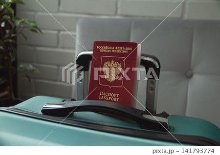 Russian Federation international passport sits in a mint green suitcase handle, symbolizing relocation, immigration, or moving abroad to new country 141793774