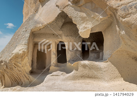 Close up view of ancient historic cave dwellings and rooms carved into volcanic tuff rock in Cappadocia, Turkey on sunny day Close up view of ancient historic cave dwellings and rooms carved into volcanic tuff rock in Cappadocia, Turkey on sunny day 141794029