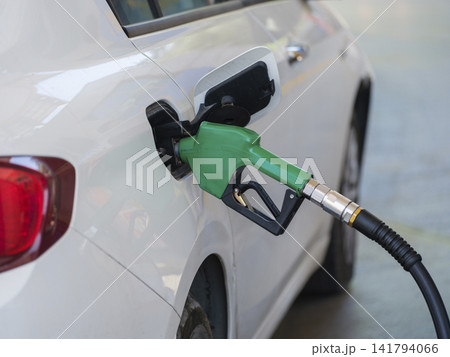 Gas pump nozzle in the fuel tank of a white car, refuel Gas pump nozzle in the fuel tank of a white car, refuel 141794066