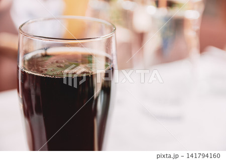 Close-up view of a refreshing dark soft drink in a tall glass cup on a table Close-up view of a refreshing dark soft drink in a tall glass cup on a table 141794160