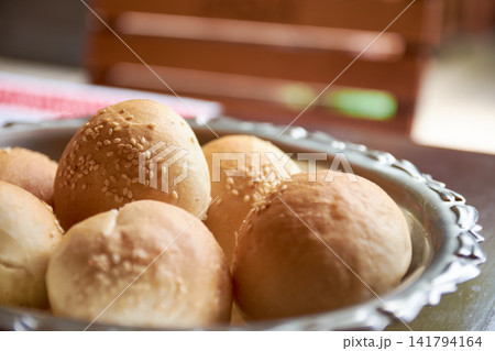 Close-up view of freshly baked bread rolls with sesame seeds in metal bowl Close-up view of freshly baked bread rolls with sesame seeds in metal bowl 141794164
