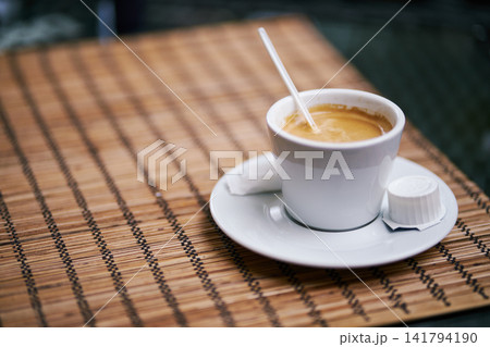 Close-up of a white ceramic cup filled with aromatic espresso on a bamboo placemat Close-up of a white ceramic cup filled with aromatic espresso on a bamboo placemat 141794190