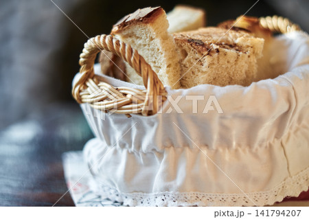 Freshly sliced artisan bread served in a small woven basket with white cloth lining Freshly sliced artisan bread served in a small woven basket with white cloth lining 141794207