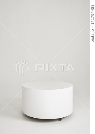 Minimalist white cylindrical pedestal on wheels in empty high key studio Minimalist white cylindrical pedestal on wheels in empty high key studio 141794485