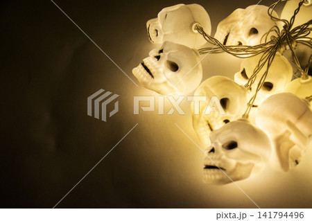 Halloween glowing yellow skull string lights hanging in the dark 141794496