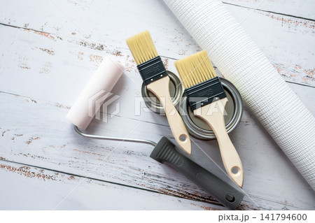 Brushes, wallpaper roll and metal can with paint for repair in a house or apartment on the white wood background. Tools for renovation. Brushes, wallpaper roll and metal can with paint for repair in a house or apartment on the white wood background. Tools for renovation. 141794600