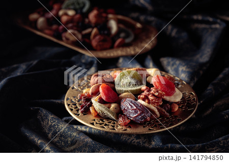 Dried tropical fruits and nuts in a golden bowl. Dried tropical fruits and nuts in a golden bowl. 141794850