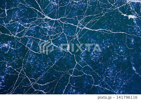 Blue paper surface with white crack lines forms dense network pattern across entire frame. Natural background, trendy color paper texture for distress, grunge design Blue paper surface with white crack lines forms dense network pattern across entire frame. Natural background, trendy color paper texture for distress, grunge design 141796116