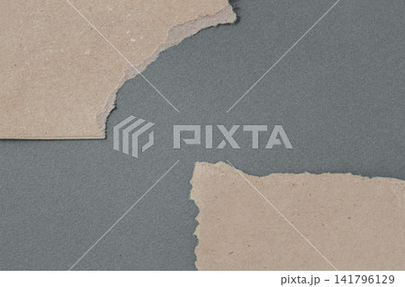 Cardboard fragments with torn edges rest on gray surface, forming open copy space for design layouts. Natural background uses cardboard texture for packaging, collage, craft, advertising Cardboard fragments with torn edges rest on gray surface, forming open copy space for design layouts. Natural background uses cardboard texture for packaging, collage, craft, advertising 141796129