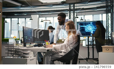Startup office manager congratulates young girl after developing artificial intelligence models for business analytics. Team leader doing fist bump with female engineers pleased by work done, camera A Startup office manager congratulates young girl after developing artificial intelligence models for business analytics. Team leader doing fist bump with female engineers pleased by work done, camera A 141796559