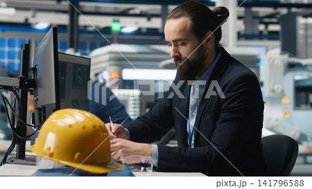 Master engineer studying production line metrics on pc and files, handling manufacturing process of photovoltaics creation to ensure clean energy. Industrial expert in modern factory. Camera B. Master engineer studying production line metrics on pc and files, handling manufacturing process of photovoltaics creation to ensure clean energy. Industrial expert in modern factory. Camera B. 141796588
